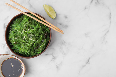 Tasty seaweed salad in bowl served on white marble table, flat lay. Space for textの写真素材