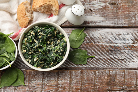 Tasty spinach dip with eggs in bowl and bread on wooden table, flat lay. Space for textの写真素材