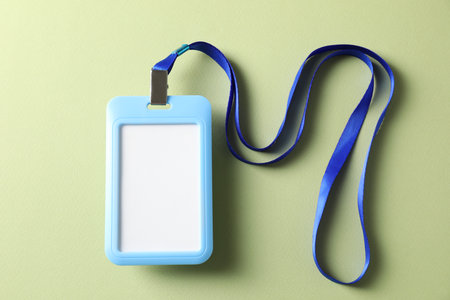 Blank light blue badge with string on green background, top view