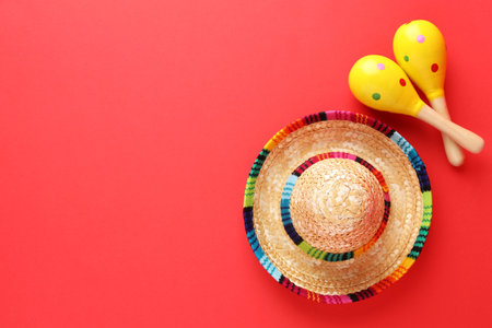 Mexican sombrero hat and maracas on red background, flat lay. Space for textの写真素材