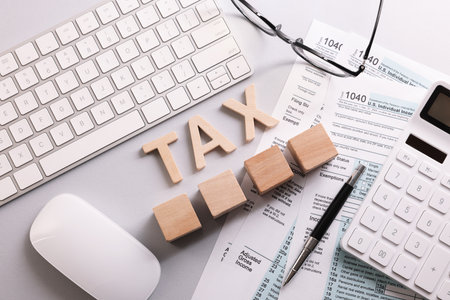 Word Tax, wooden cubes, calculator, keyboard and documents on light gray table, flat layの写真素材