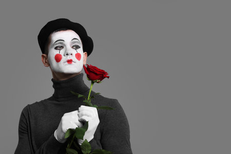 Portrait of mime artist with red rose on grey background. Space for textの写真素材