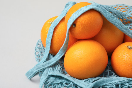 String bag with fresh oranges on light background, closeup. Space for textの写真素材