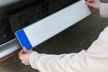 Woman installing vehicle registration plate outdoors, closeupの写真素材