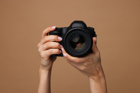 Photographer with camera on brown background, closeupの写真素材