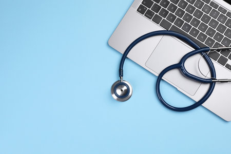 Laptop and stethoscope on light blue background, flat lay. Space for textの写真素材