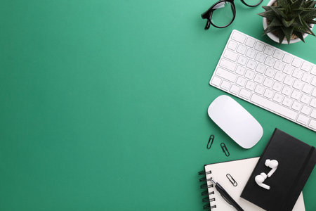 Flat lay composition with different office stationery on green table, space for text