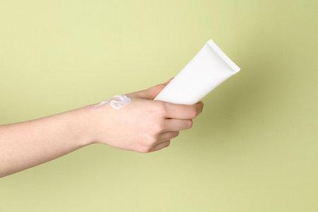 Woman with tube of cream on green background, closeupの写真素材