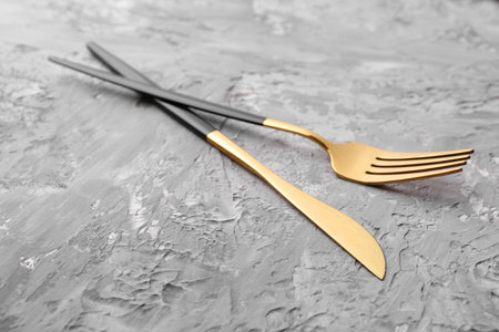 Elegant cutlery. Stylish knife and fork on gray textured table, closeupの写真素材
