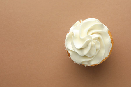 Tasty vanilla cupcake with cream on dark beige background, top view. Space for textの写真素材
