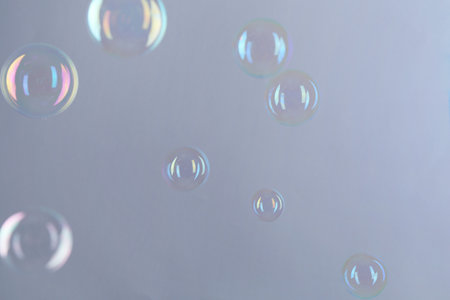 Beautiful transparent soap bubbles on gray background