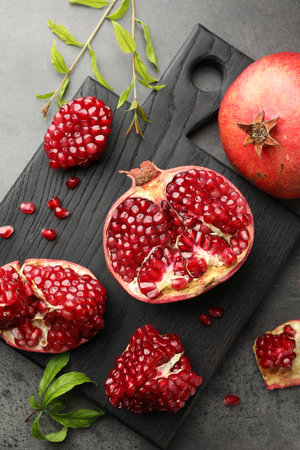 Fresh pomegranates and green leaves on gray table, top viewの写真素材