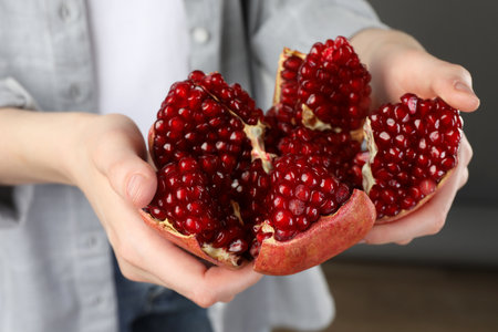 Woman holding fresh pomegranate on gray background, closeupの写真素材