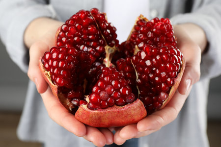 Woman holding fresh pomegranate on gray background, closeupの写真素材