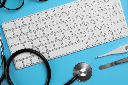 Keyboard, stethoscope, thermometer and tweeters on light blue background, flat lay