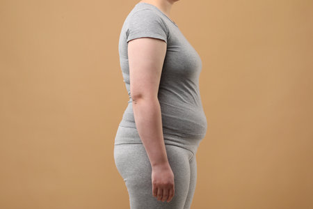 Overweight woman in gray clothes on beige background, closeupの写真素材