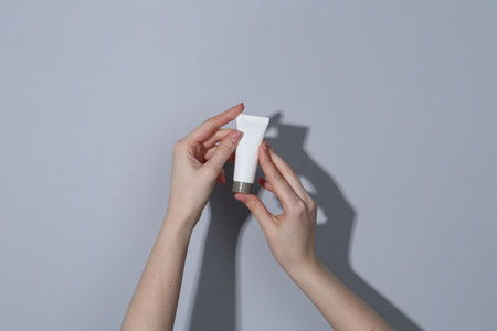 Woman holding tube of cream on gray background, closeupの写真素材