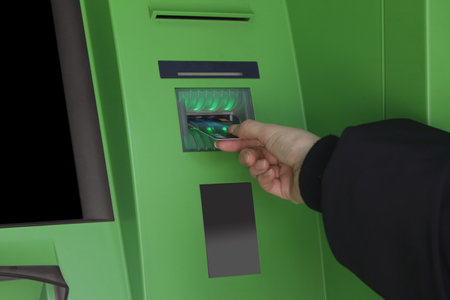 Woman inserting credit card into green cash machine, closeupの写真素材