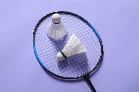 Feather badminton shuttlecocks and racket on violet background, top viewの写真素材