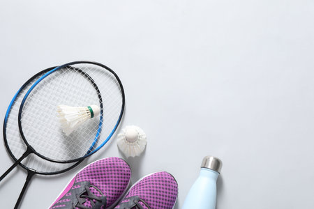 Feather badminton shuttlecocks, rackets, sneakers and bottle on gray background, flat lay. Space for textの写真素材