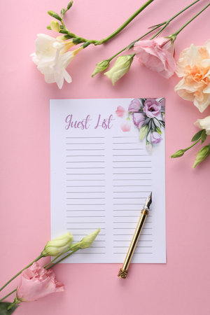 Guest list, pen and beautiful flowers on pink background, flat lay. Space for textの写真素材
