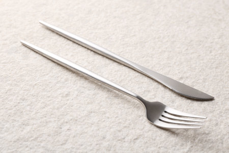 Stylish cutlery. Silver knife and fork on light textured table