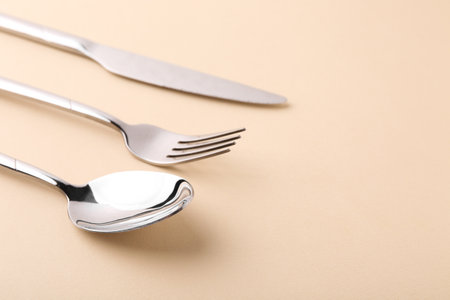 Stylish silver cutlery set on beige background, closeup. Space for textの写真素材
