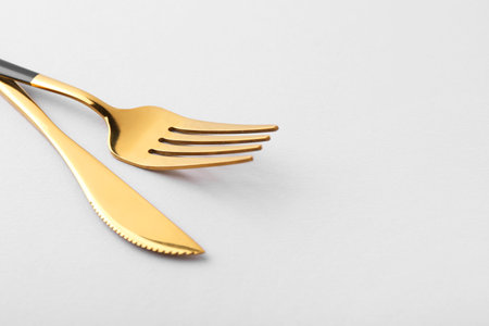 Stylish cutlery. Golden knife and fork on gray background, closeup. Space for textの写真素材