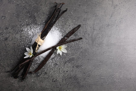 Vanilla pods, sugar and flowers on gray table, flat lay. Space for textの写真素材