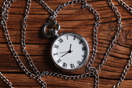 Silver pocket clock with chain on wooden table, top viewの写真素材