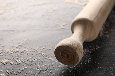 Scattered flour and rolling pin on dark textured table, closeup. Space for textの写真素材