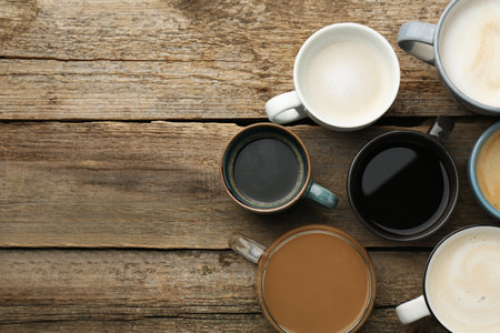 Different coffee drinks in cups on wooden table, flat lay. Space for textの写真素材