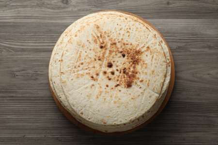 Many tasty homemade tortillas on wooden table, top view