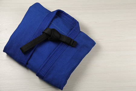 Black karate belt and blue kimono on wooden background, top view. Space for textの写真素材