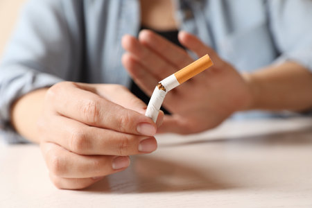 Stop smoking. Woman holding broken cigarette at table, closeupの写真素材