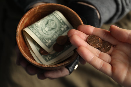 Woman giving coins to poor homeless man with bowl of donations, closeupの写真素材