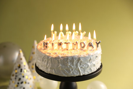 Tasty birthday cake with burning candles on green background, closeupの写真素材