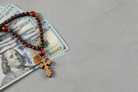 Wooden cross and money on gray table. Space for text
