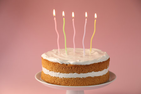 Tasty cake with colorful candles on pink background, closeup