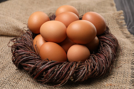 Fresh chicken eggs in nest on burlap fabric, closeup