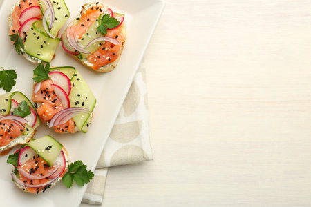 Tasty canapes with salmon served on white wooden table, top view. Space for text