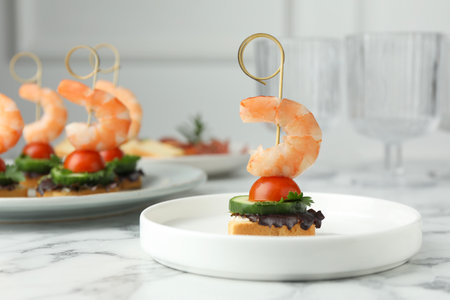 Tasty canapes with shrimps, cucumber, greens and tomatoes on white table marbleの写真素材