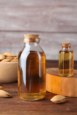 Almond oil in bottles and bowl with nuts on wooden table, closeupの写真素材