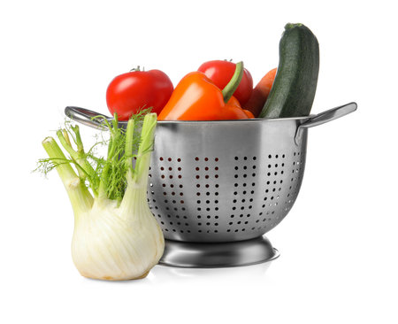 Colander with fresh vegetables isolated on whiteの写真素材