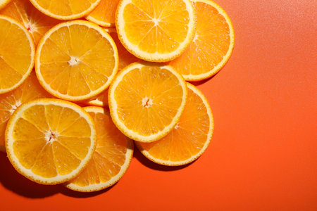 Slices of juicy orange on terracotta background, top view. Space for text