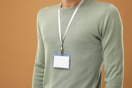 Man with blank badge on light brown background, closeup