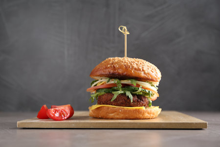 Board with delicious vegetarian burger on gray tableの写真素材