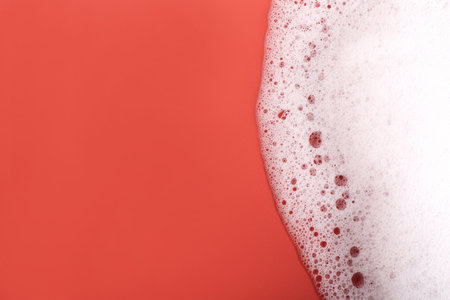 White foam with bubbles on red background, top view. Space for text