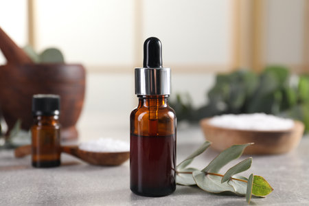 Aromatherapy. Bottle of essential oil and eucalyptus leaves on gray tableの写真素材