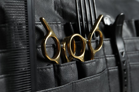 Hairdresser tools. Professional scissors and combs in leather organizer, closeup